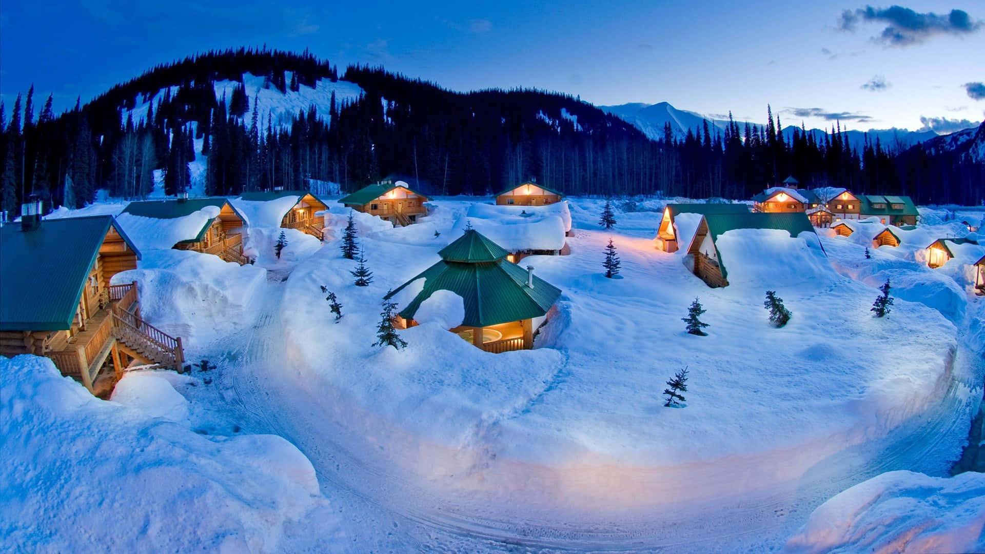 積雪的小屋亮著溫暖的燈光，坐落在暮色中的山林裡。