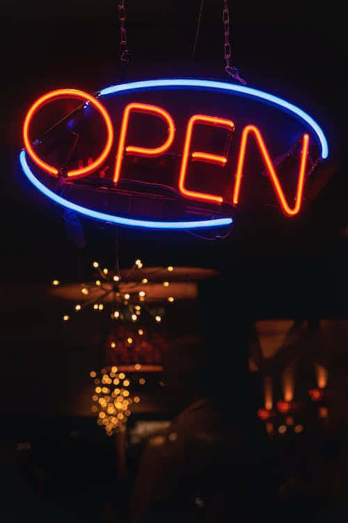 一個明亮的紅藍色霓虹燈牌OPEN，懸掛在昏暗的空間中。