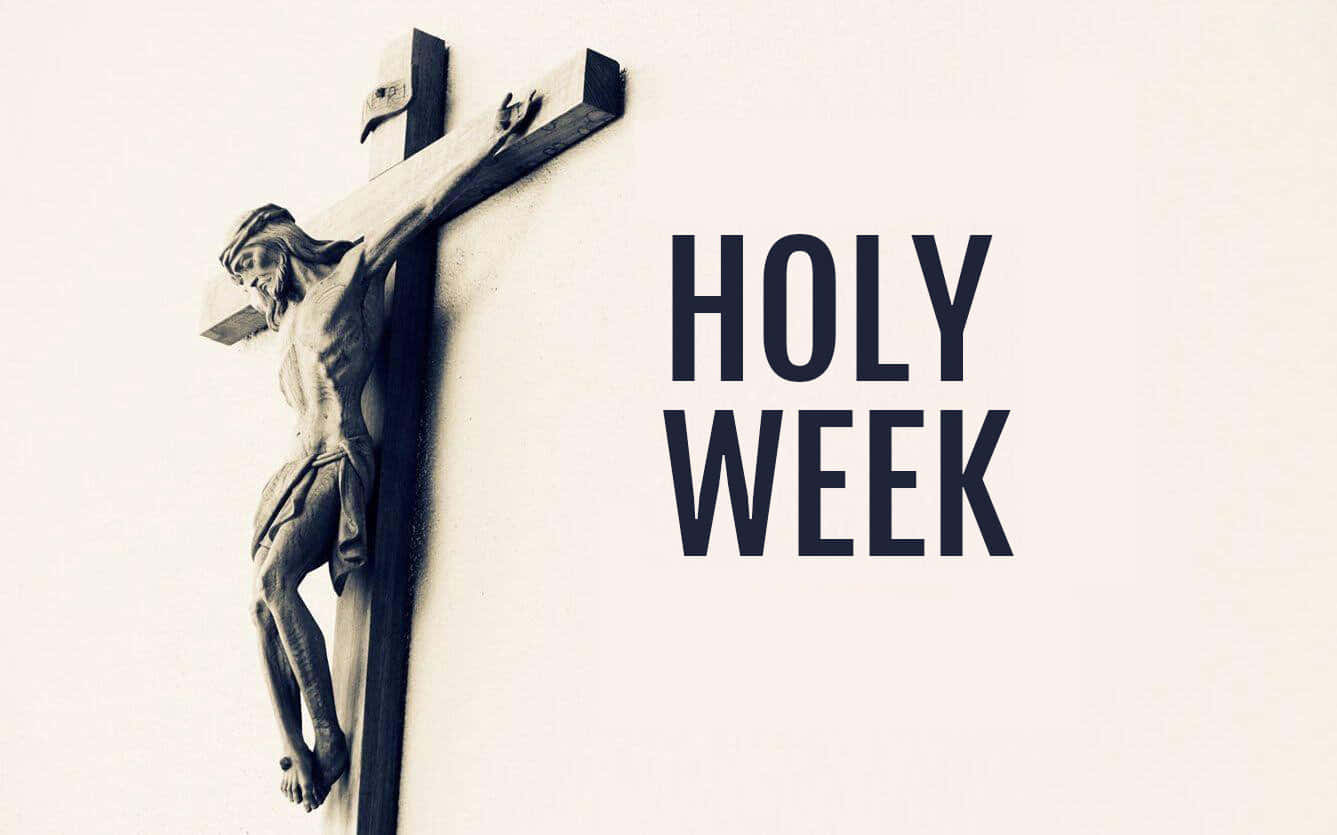 享受聖週的色彩繽紛慶祝 壁紙 — 一個莊嚴的耶穌石製 crucifixion 雕像掛在素牆上，旁邊有粗體黑色文字寫著「HOLY WEEK」。