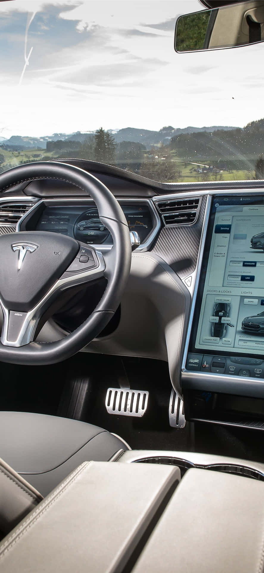 Tesla 車廂內部，配備數碼儀表板和擋風玻璃外的山景。