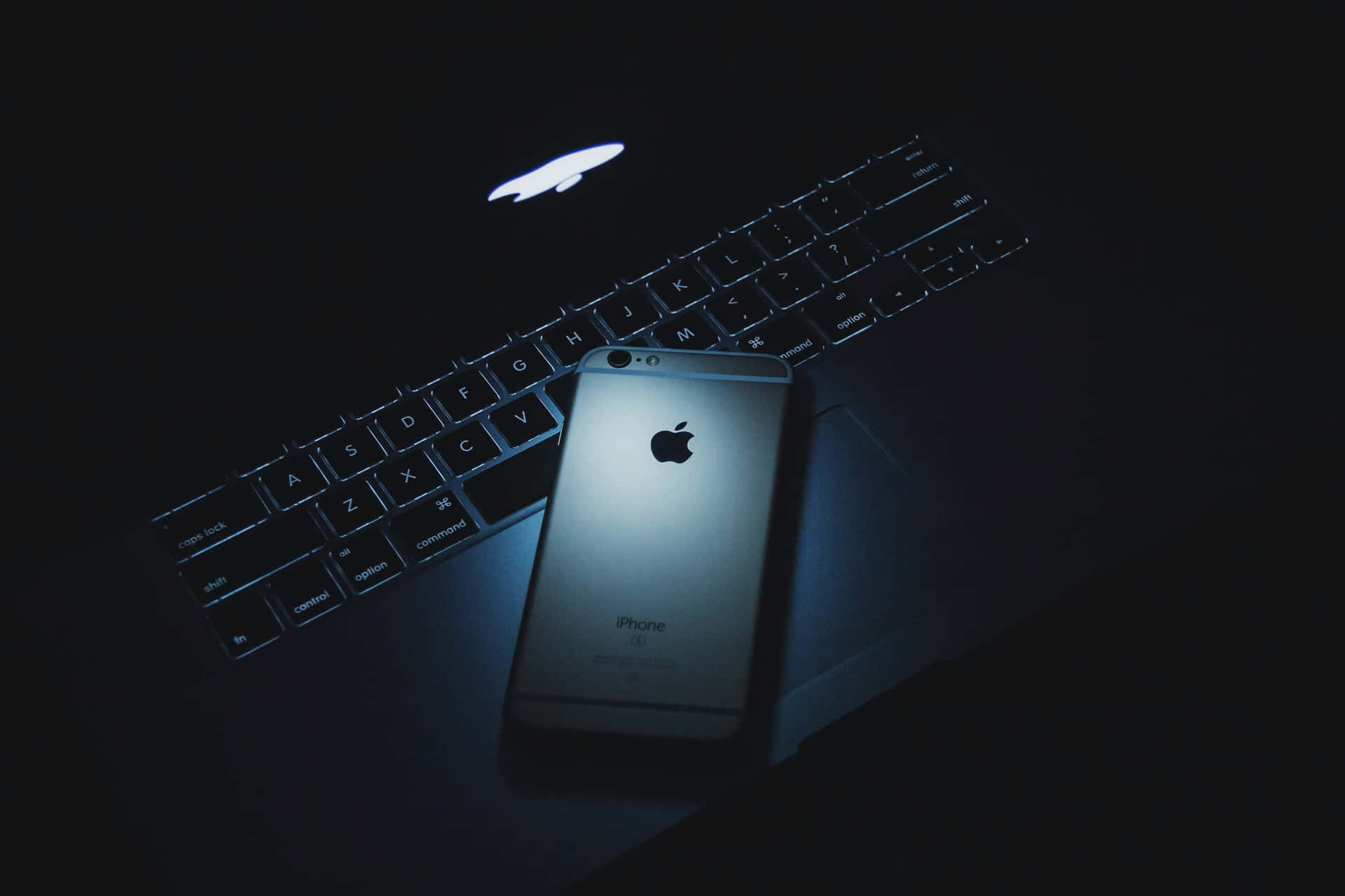 銀色iPhone在筆記型電腦鍵盤上，昏暗藍光