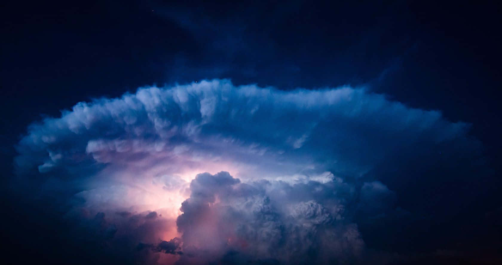 享受色彩繽紛的夏日天空 壁紙 — 巨大的風暴雲在黑暗的夜空中發出電紫色和藍色的光芒。