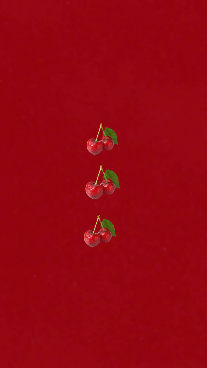 三對帶有綠色葉子的紅櫻桃垂直漂浮在紅色背景上。