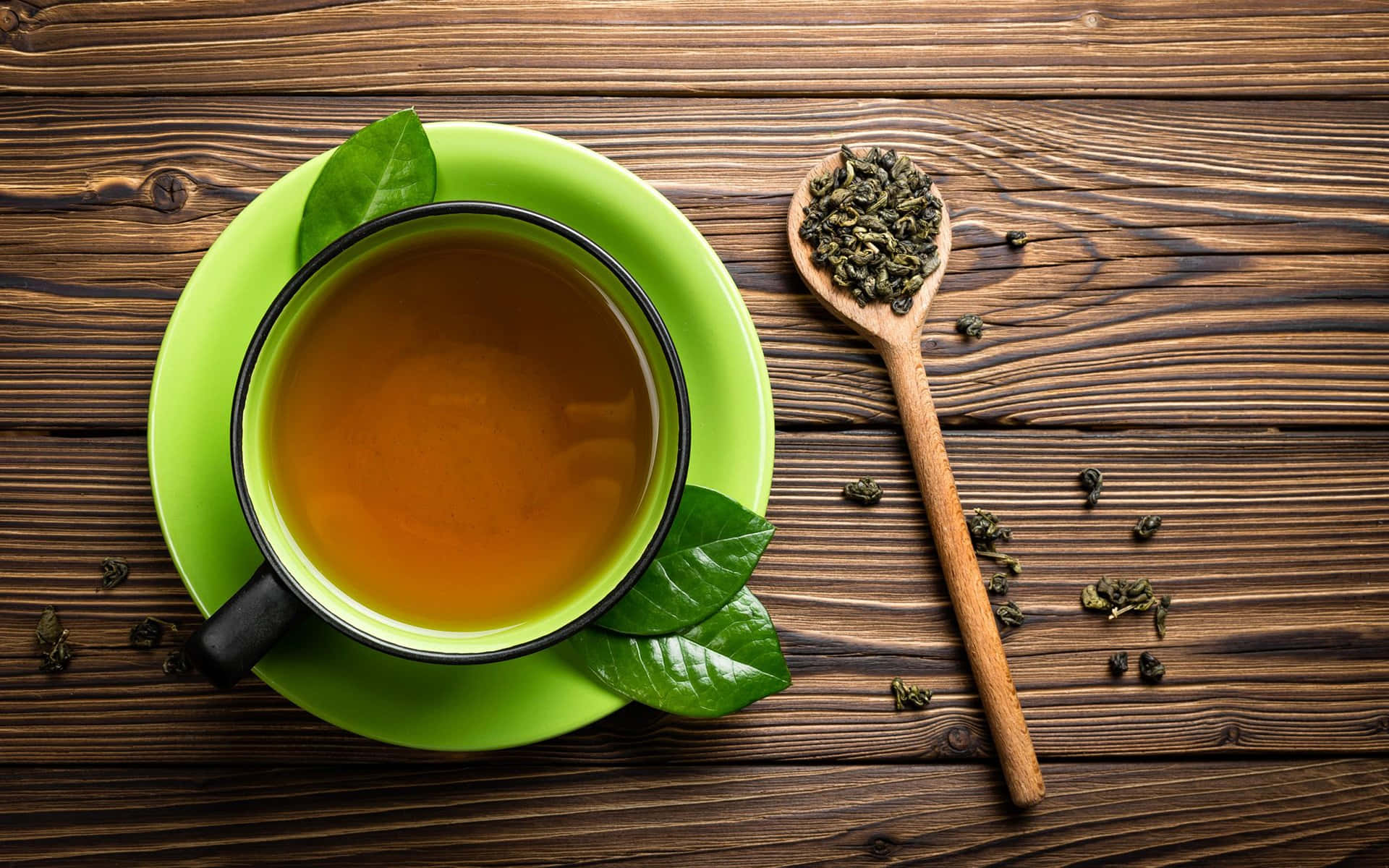 木桌上放著一杯帶有新鮮葉子的綠茶。