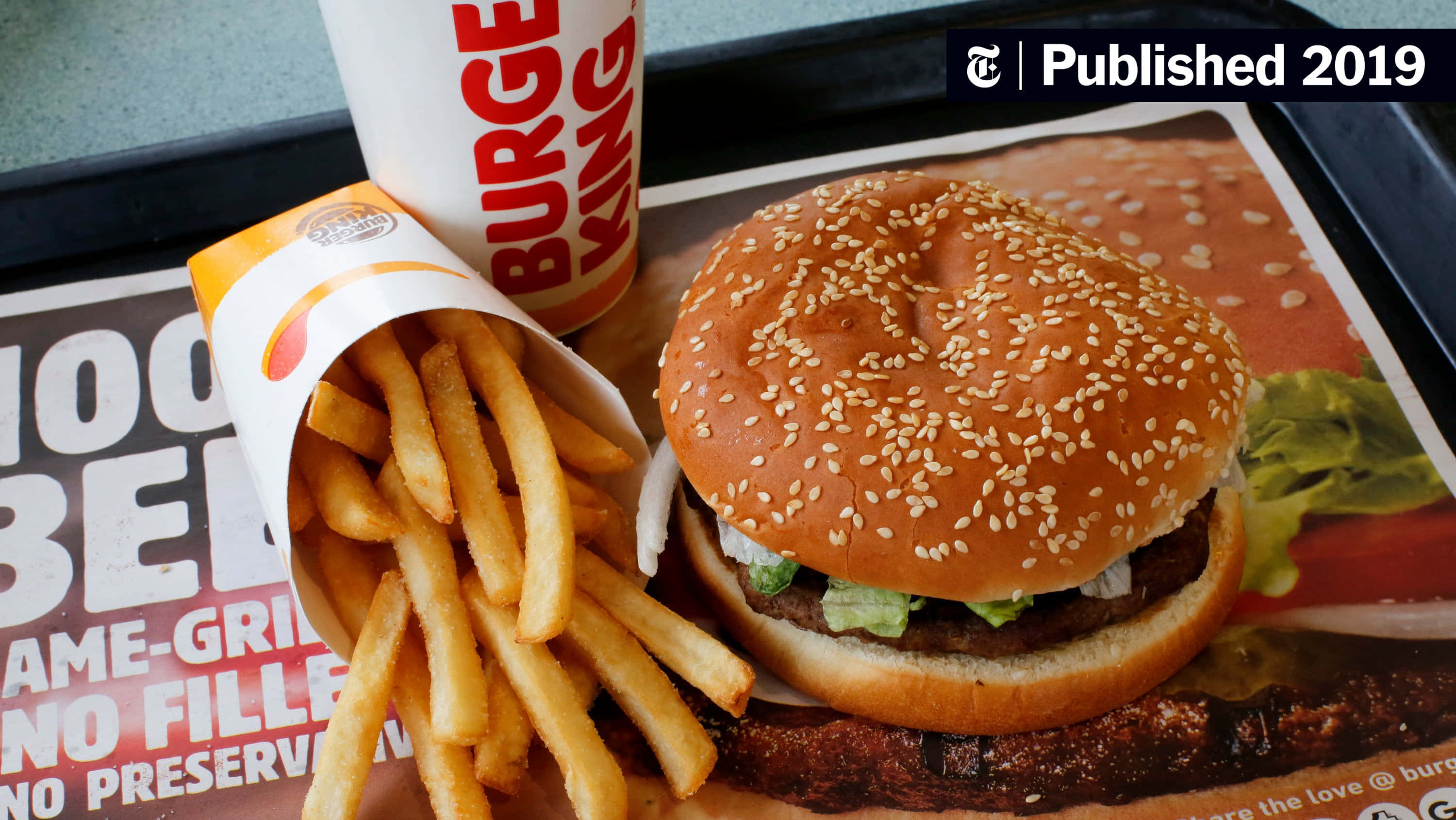 享受速食美味，活出快節奏人生 壁紙 — Burger King托盤上芝麻漢堡和脆薯條的特寫，附有品牌紙。