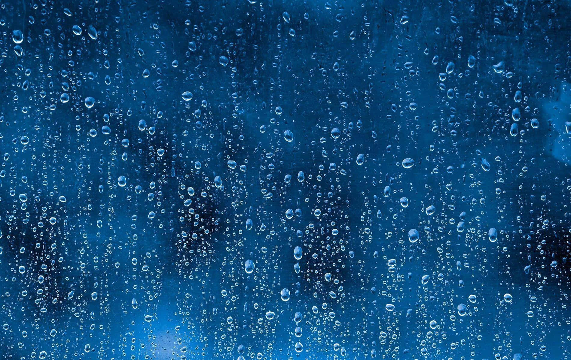 雨滴在藍色背景的玻璃窗上滑落。
