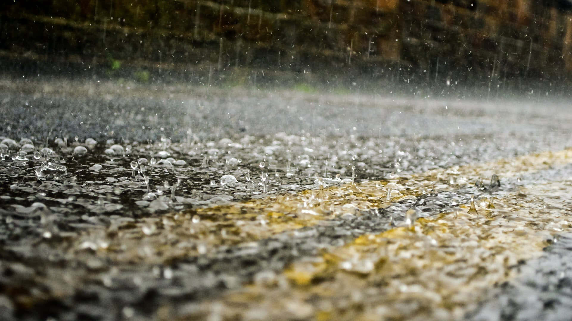 雨滴打在濕漉漉的瀝青路上，有黃線