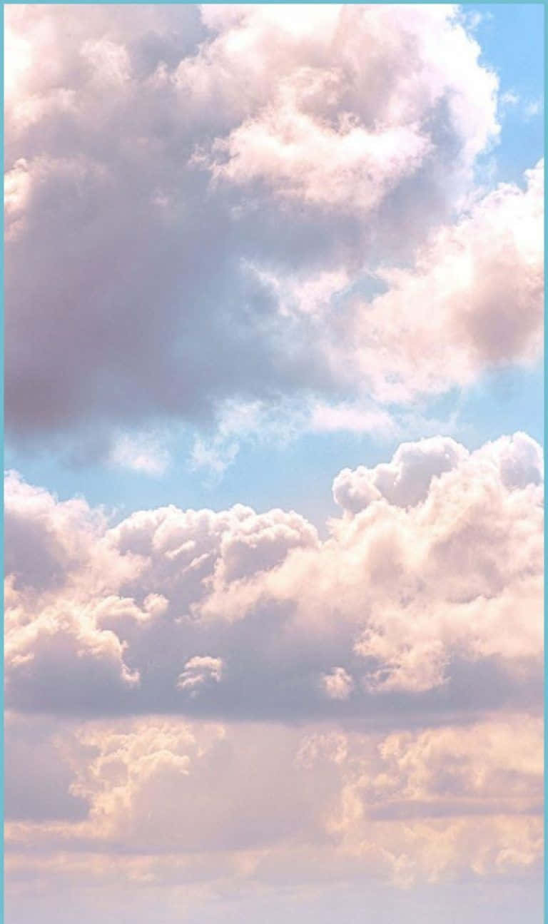 享受雲端晴日 壁紙 — 廣闊的天空充滿了柔和的粉彩雲朵，在溫暖的日落色調中閃耀，映襯著淡藍色的背景。