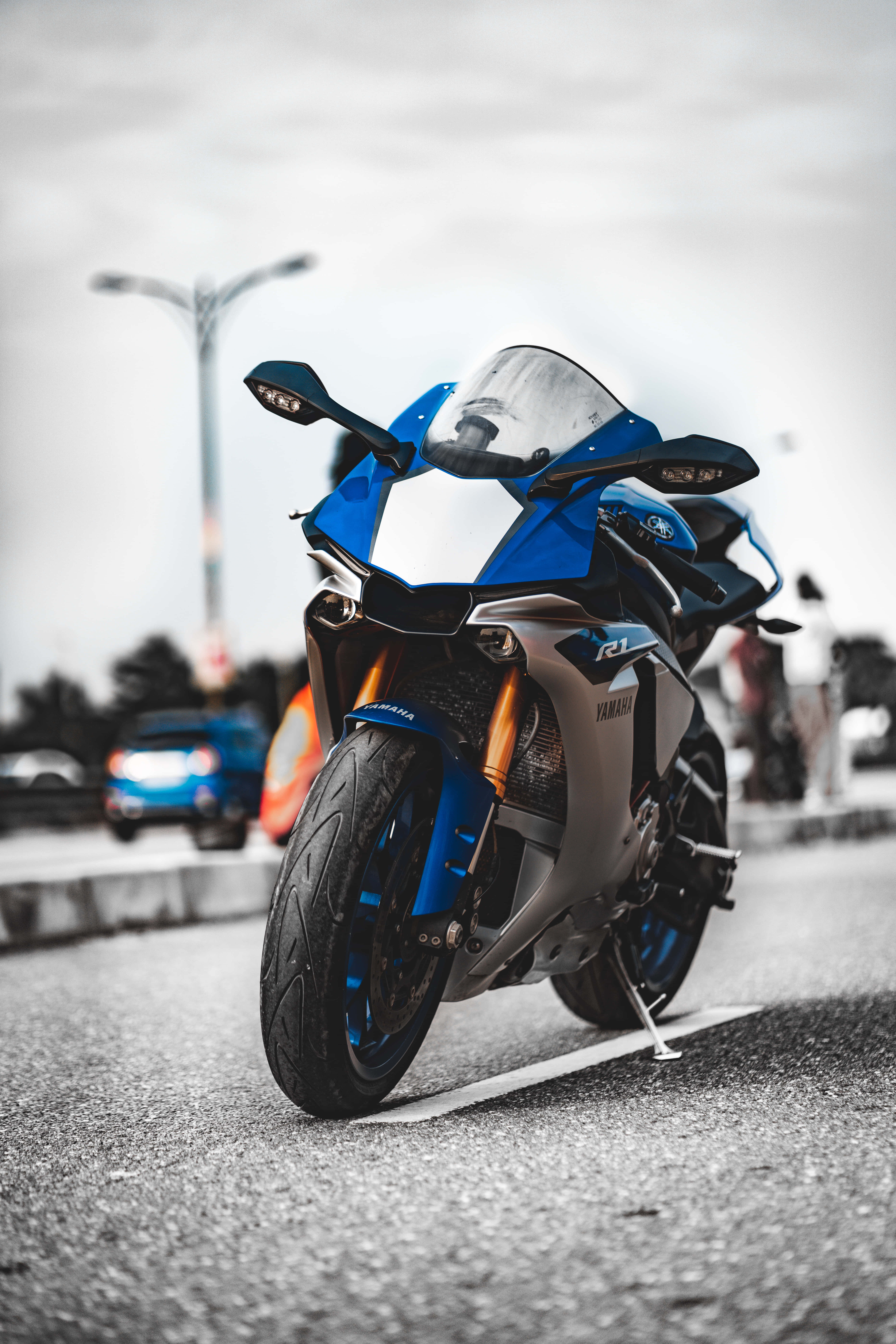 享受騎乘摩托車的刺激 壁紙 — 一架搶眼的藍色Yamaha R1電單車停泊在瀝青路上，背景是模糊的城市景色。