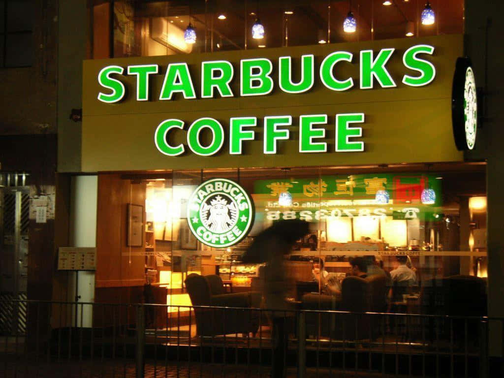 夜晚的Starbucks咖啡店，帶有發光標誌和模糊的顧客在內。