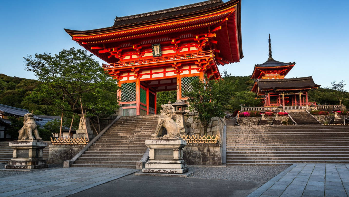 日落時分的紅色日本寺廟大門和石獅。