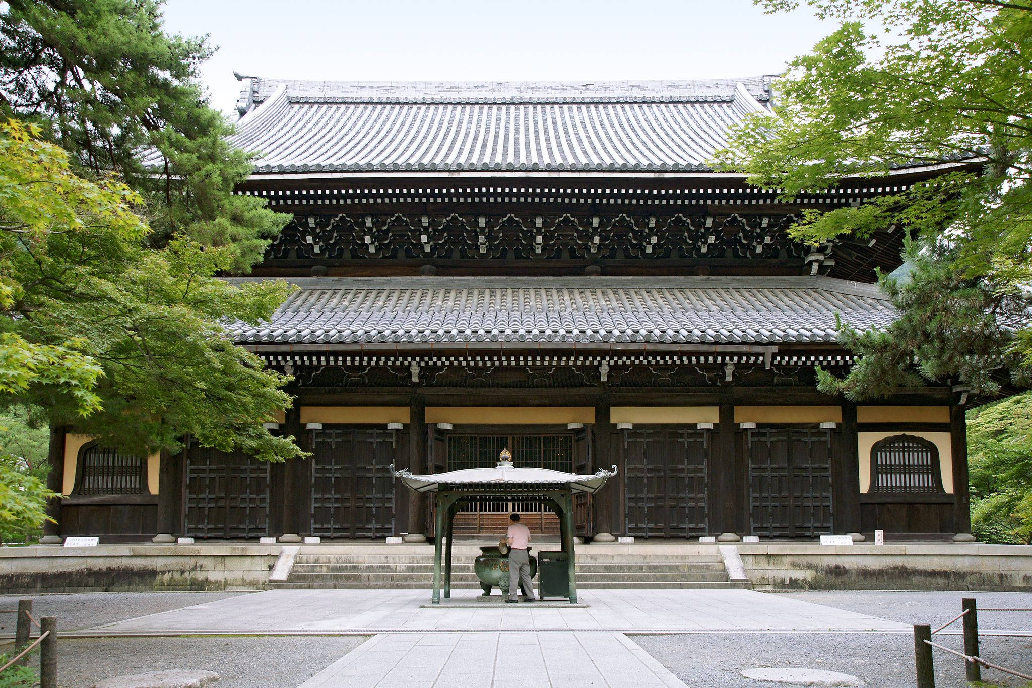 京都南禅寺 壁紙 — 傳統日本寺廟，深色木結構和瓦片屋頂，周圍環繞著茂密的綠樹，天空多雲。