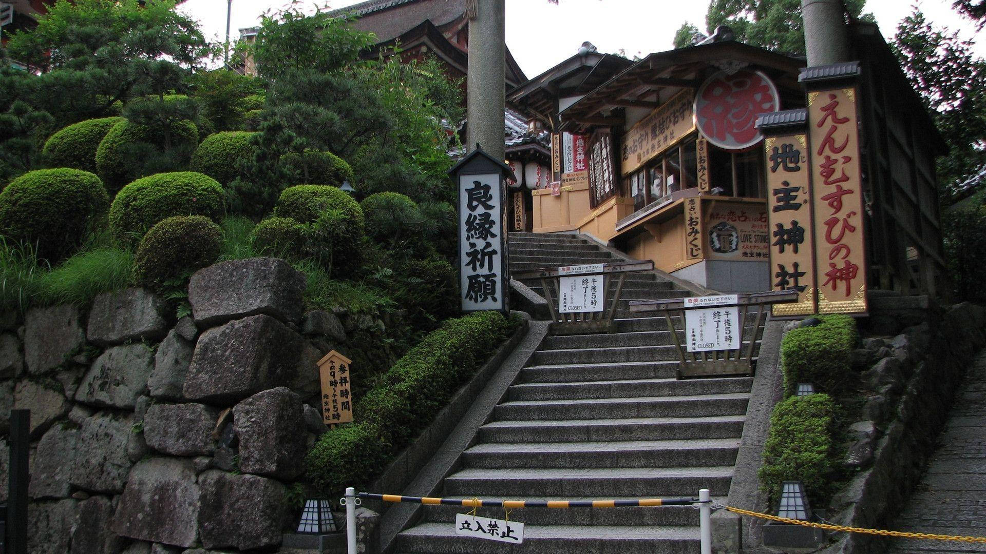 通往日本神社的石階，周圍是茂密的綠植和石牆。