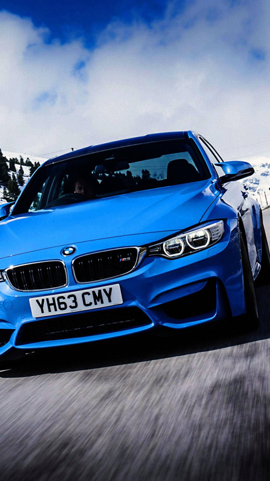 藍色BMW M4在積雪山路上飛馳，上方有雲。