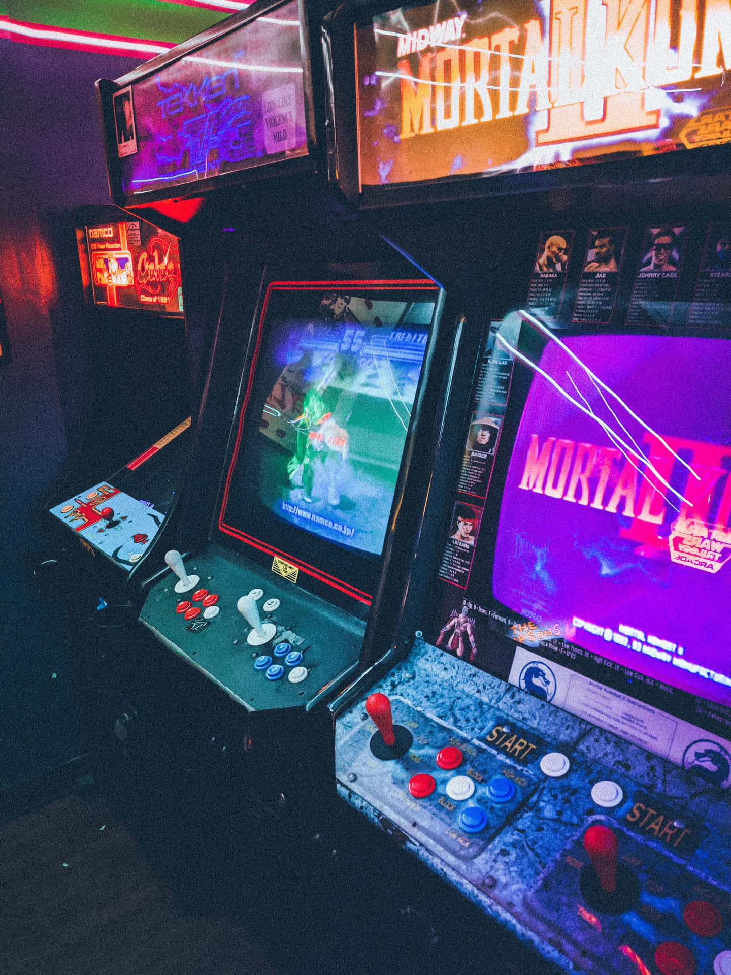 在黑暗的遊戲室中，霓虹燈照亮的街機配備 Mortal Kombat II。
