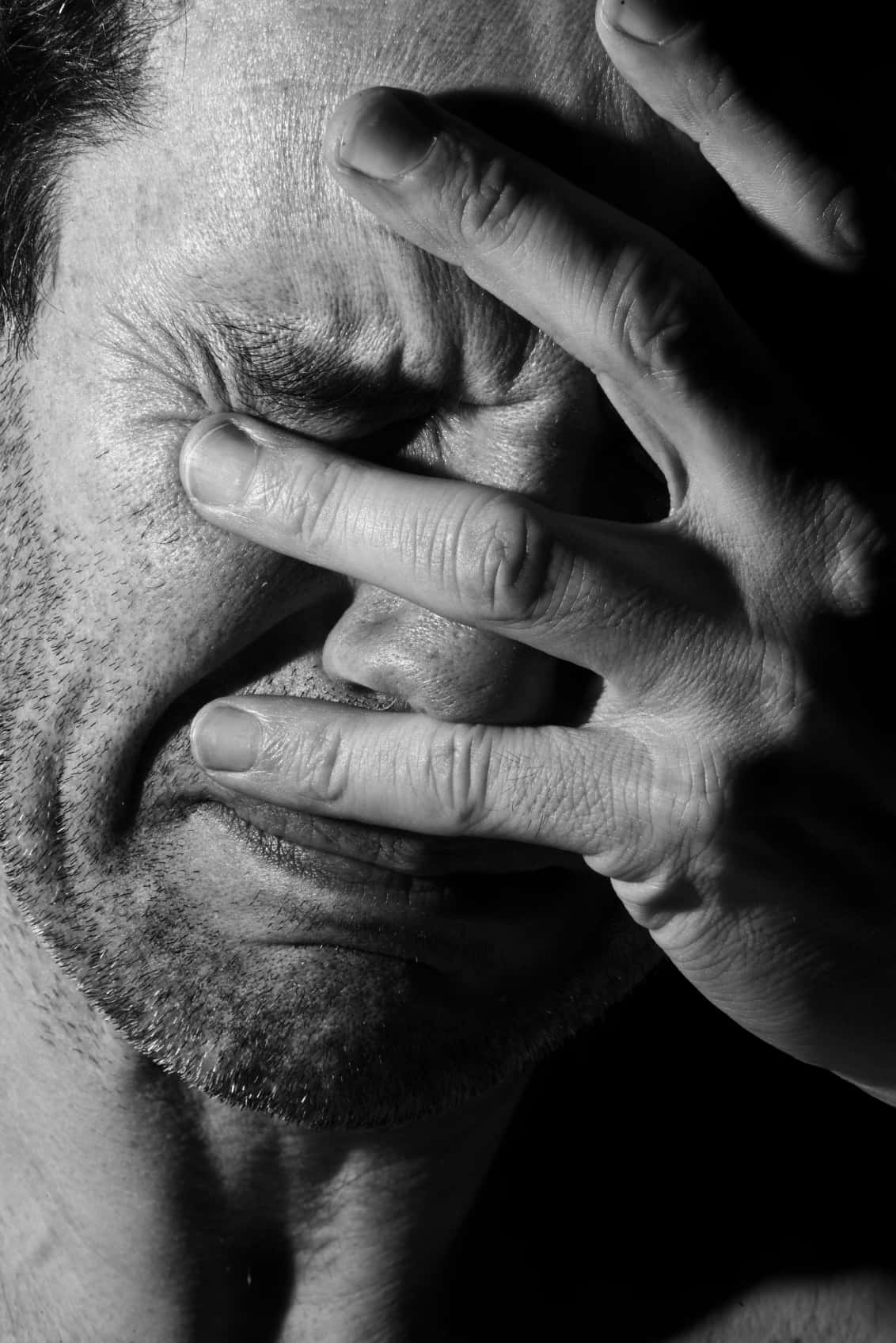 人生充滿意想不到的情感。 壁紙 — 一個男人的黑白臉孔，手遮住眼睛，處於極度痛苦或絕望的時刻。