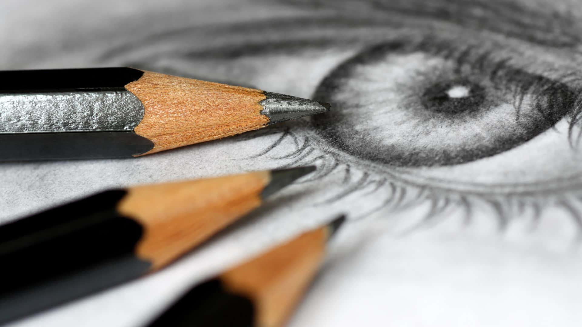 人眼鉛筆素描插畫 壁紙 — 一個特寫，描繪了一個詳細的鉛筆素描眼睛，削尖的鉛筆放在紙上。
