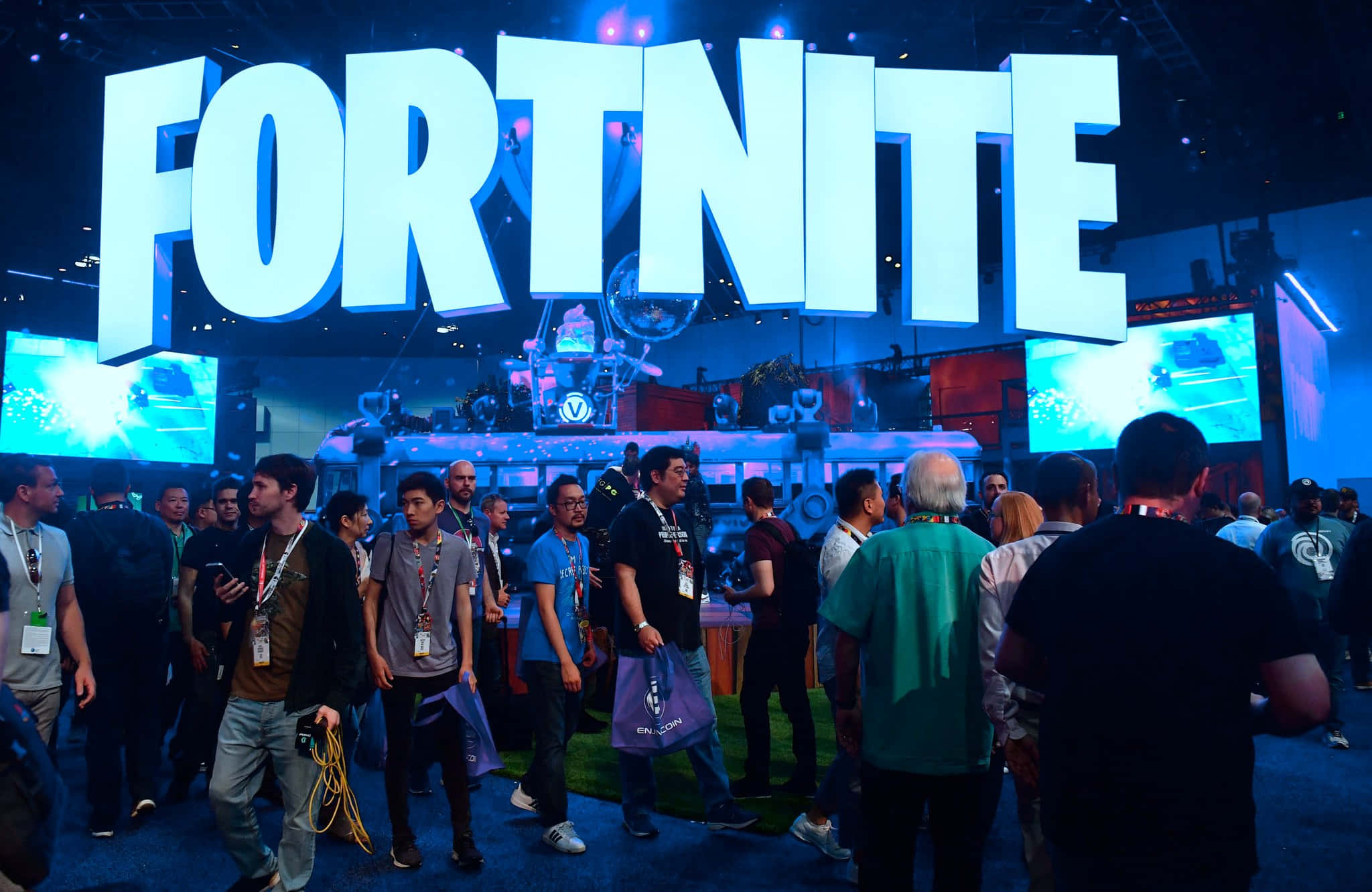 Gaming Conventions 桌布 壁紙 — 人群聚集在一個充滿活力的遊戲展攤位，上方是一個巨大的發光Fortnite標誌。