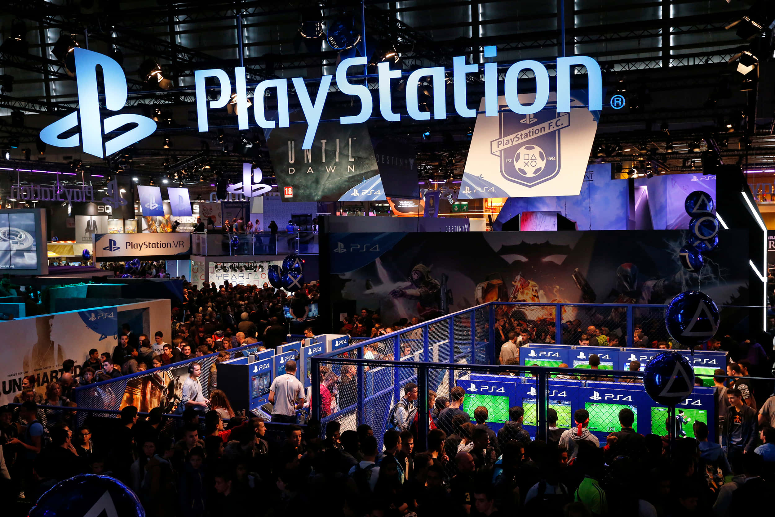 Gaming Conventions 桌布 壁紙 — 人群聚集在發光的PlayStation標誌下，於繁忙的遊戲展攤位中。