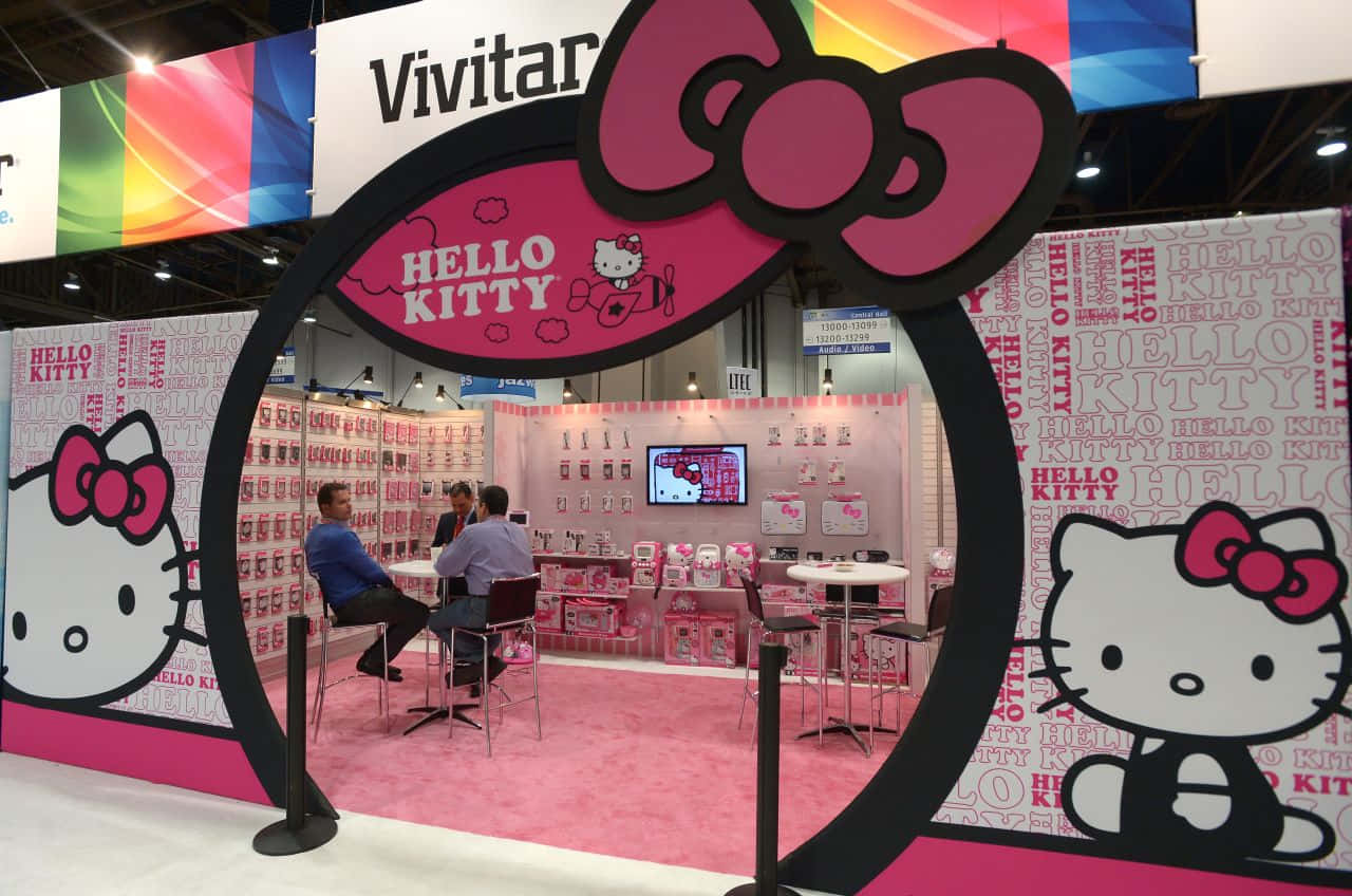 什麼比Hello Kitty更可愛？ 壁紙 — 一個充滿活力的粉紅色Hello Kitty品牌展位，設有大型角色剪影和瀏覽產品的參觀者。