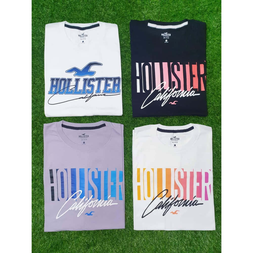 綠色草地上四件摺疊好的Hollister California T恤。