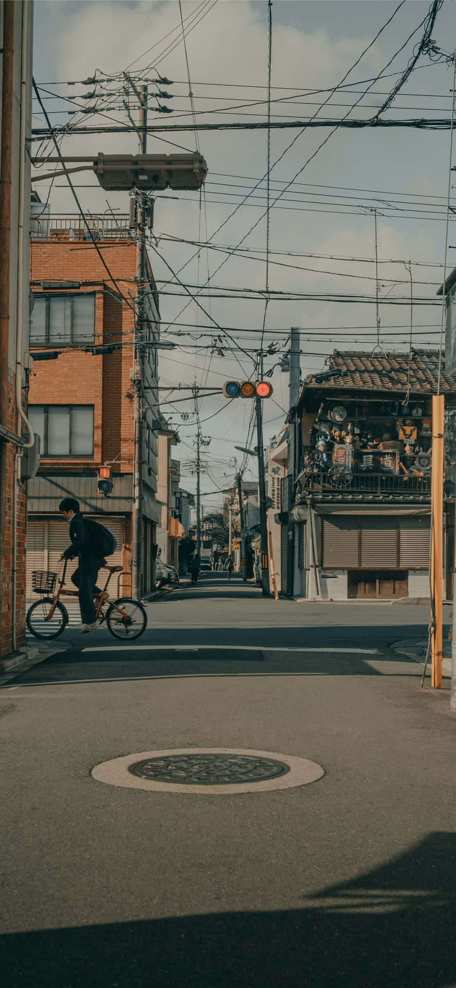 一個人在有建築物和電線的狹窄城市街道上騎單車。
