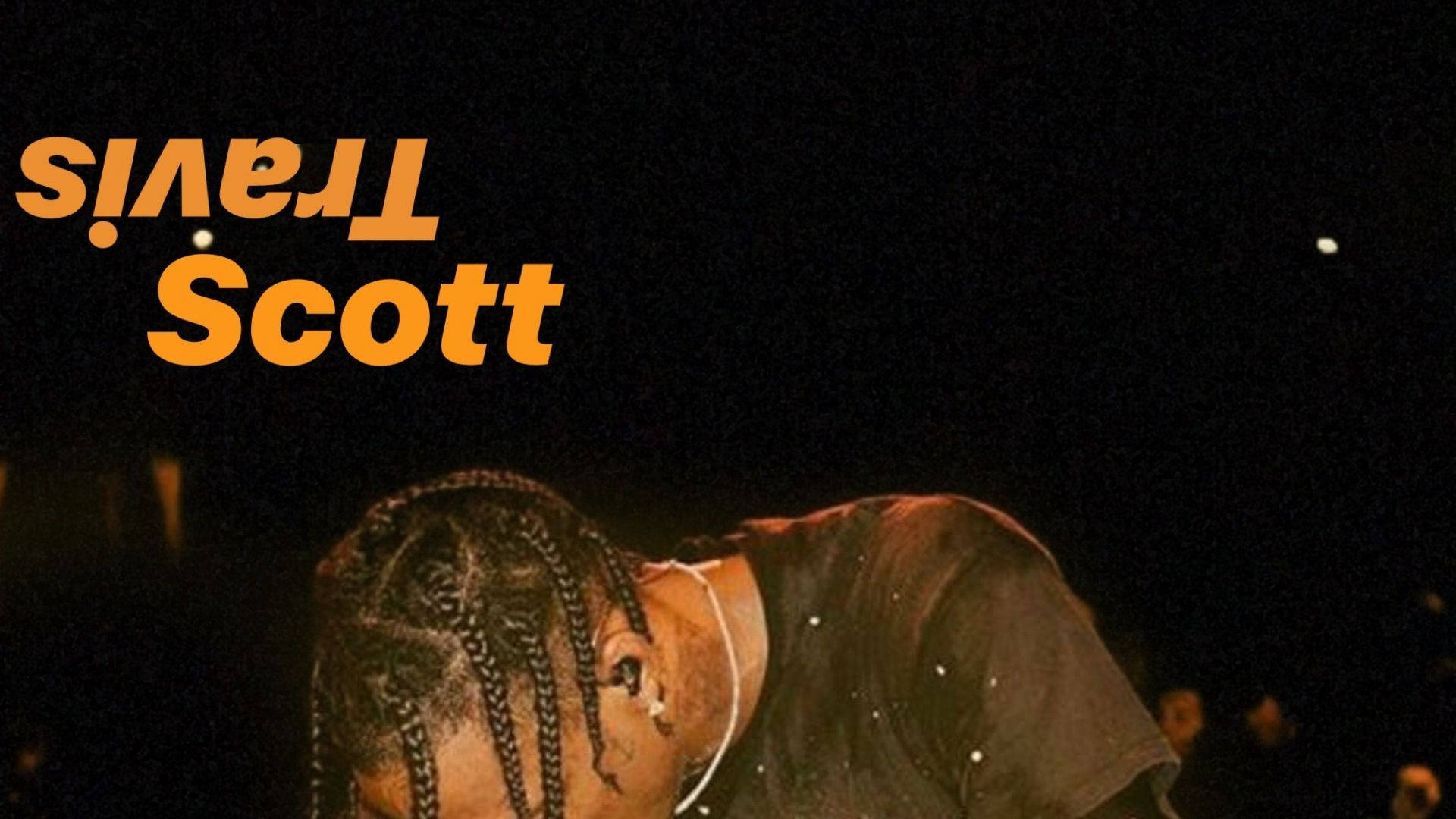 Travis Scott 在舞台燈光下以辮子造型表演。
