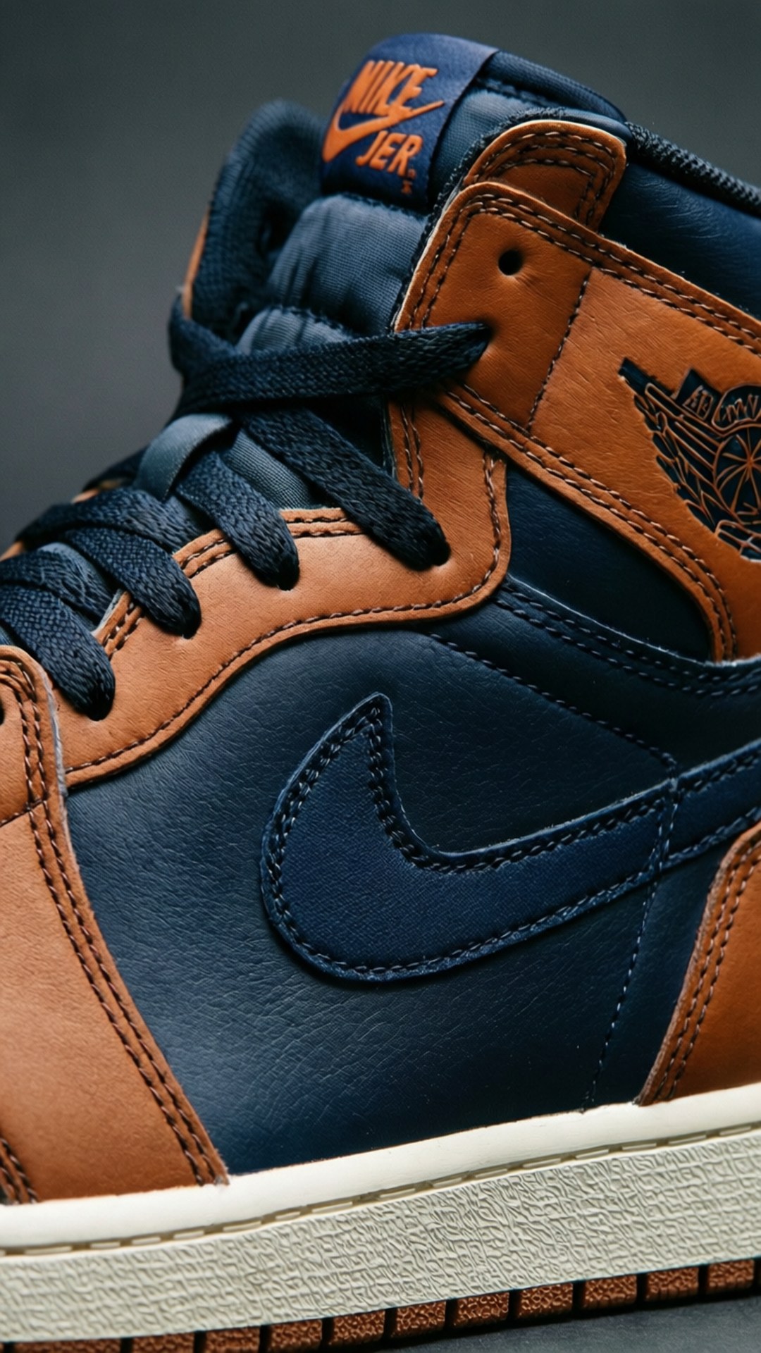 仙人掌傑克 Air Jordan 1 特寫 壁紙 — 海軍藍和棕褐色 Nike Air Jordan 1 運動鞋的特寫，帶有橙色點綴和白色鞋底。