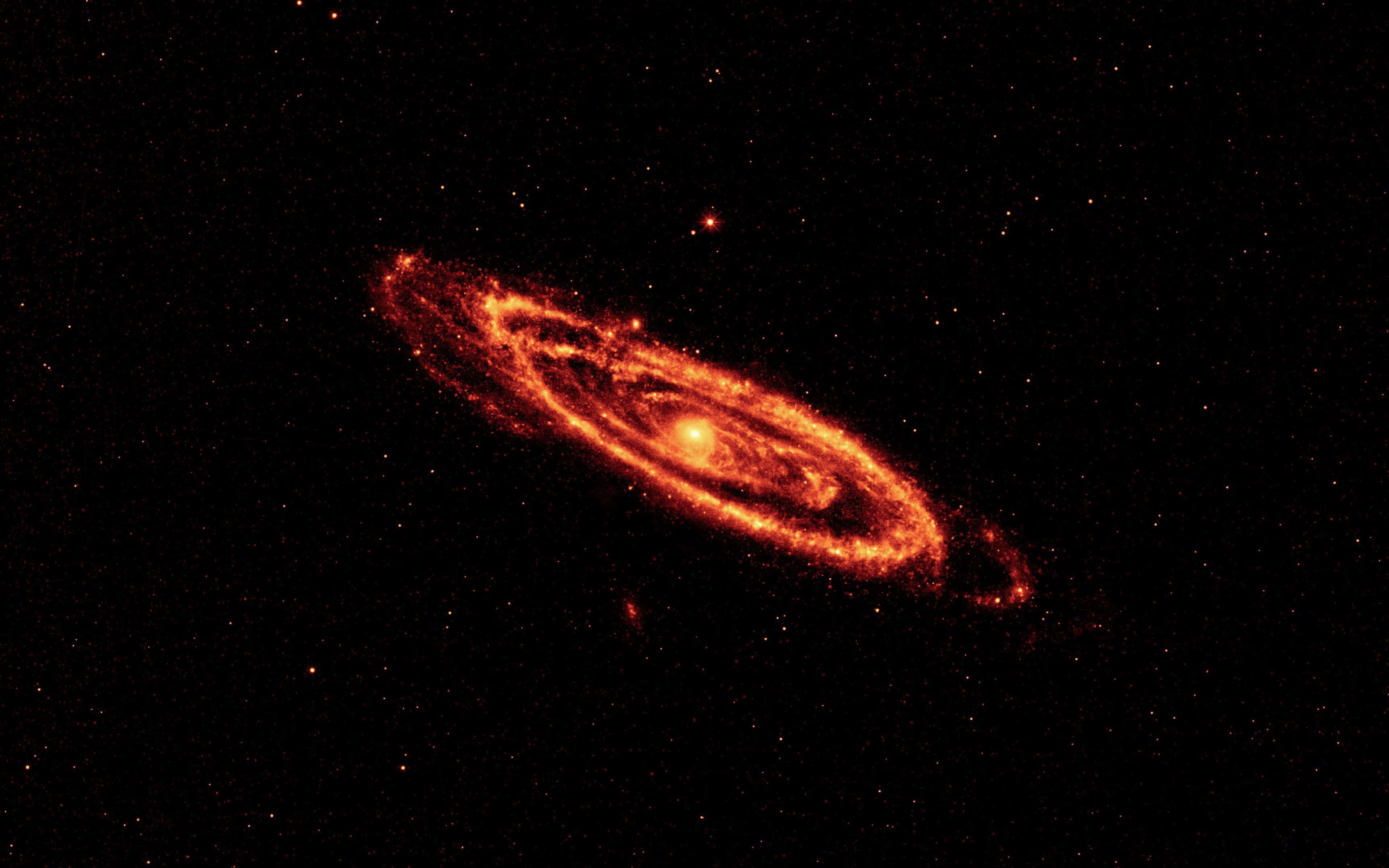 仙女座星系的壯麗宇宙景觀 壁紙 — 一個熾熱的螺旋星系在佈滿星星的黑色虛空中散發出橙色和紅色的光芒。