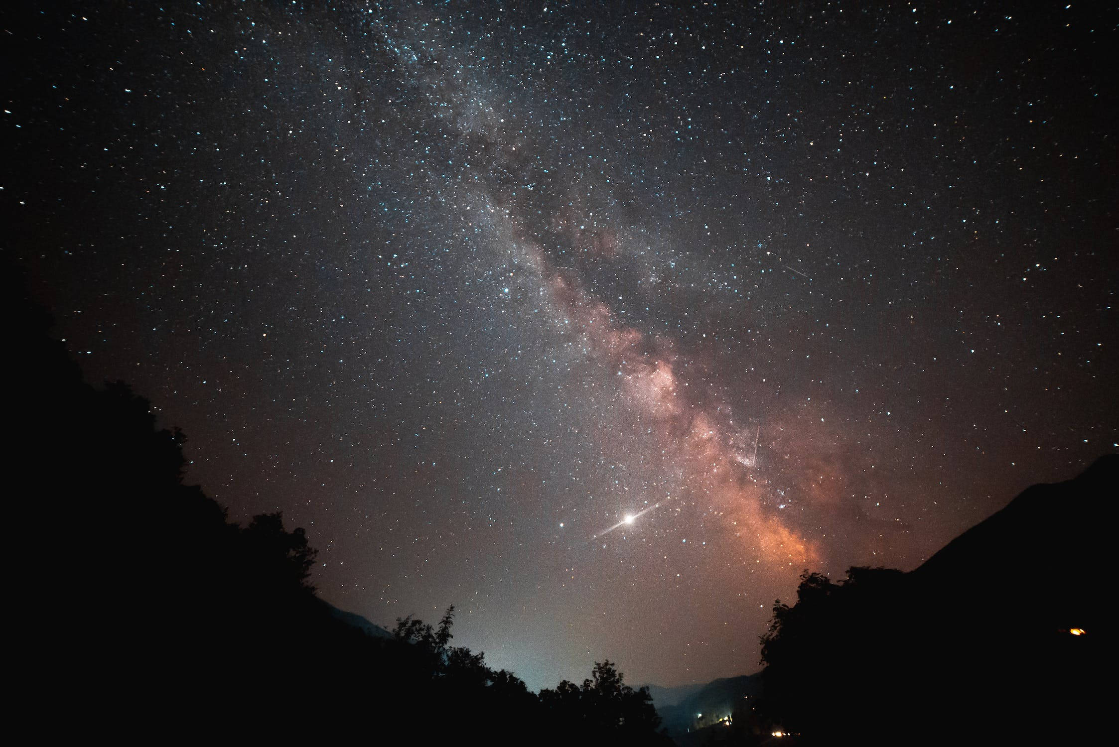 星星 桌布 壁紙 — 令人嘆為觀止的夜空，佈滿星星和銀河，在黑暗的山巒剪影上方拱起，一顆明亮的流星劃過天際。