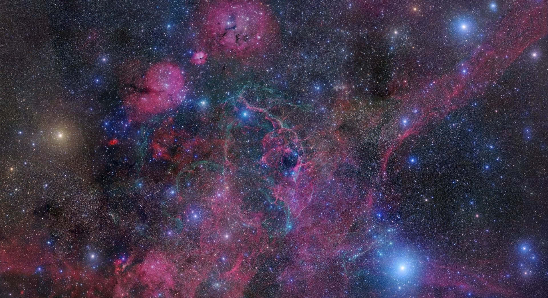 Colorful Space 桌布 壁紙 — 令人嘆為觀止的宇宙景觀，發光的粉紅色和藍色星雲在深邃的黑色虛空中與無數恆星旋轉交織。