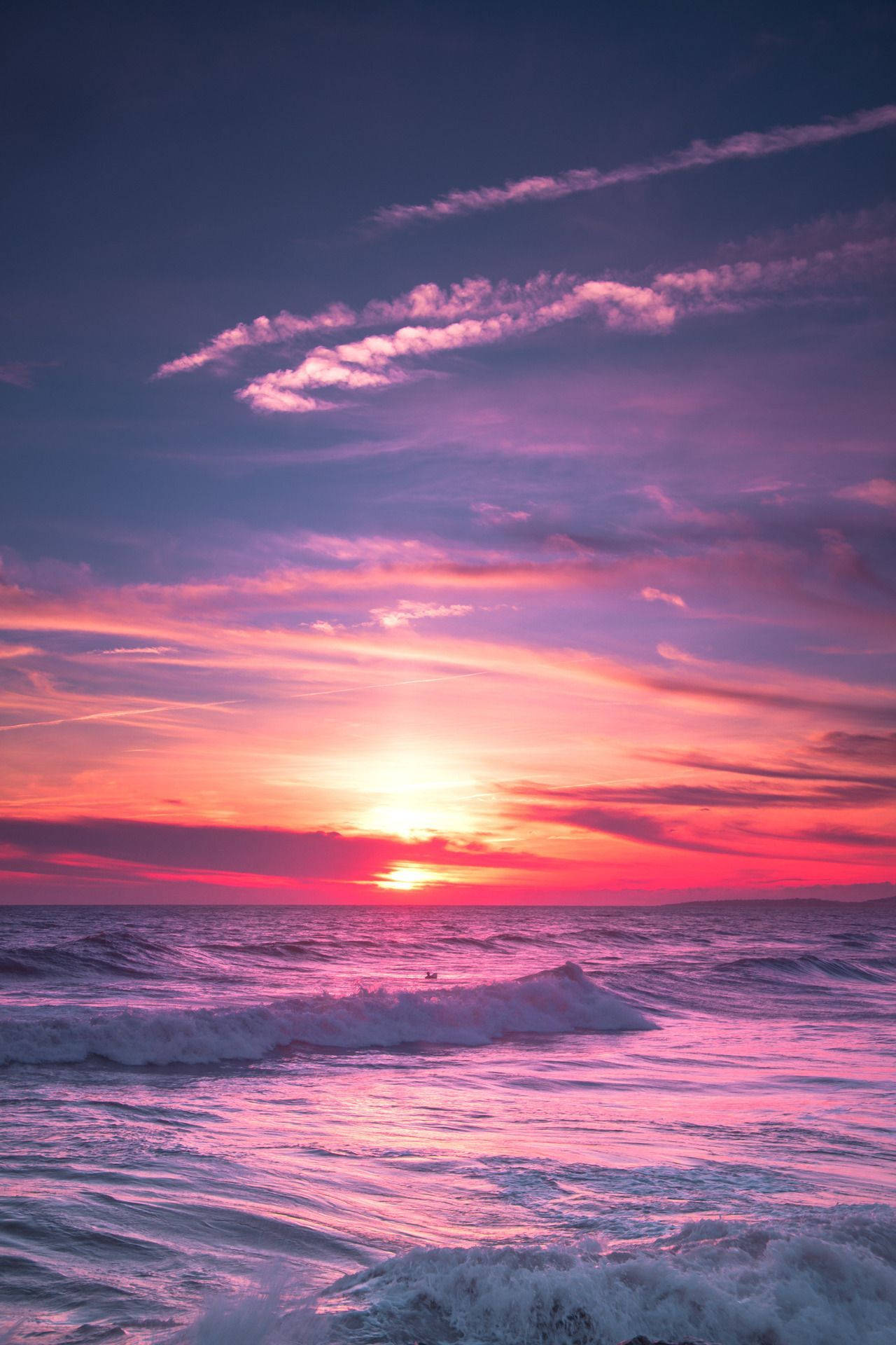 Aesthetic Sunset 桌布 壁紙 — 令人嘆為觀止的海洋日落，火紅的粉紅色和橙色雲彩倒映在波浪上。