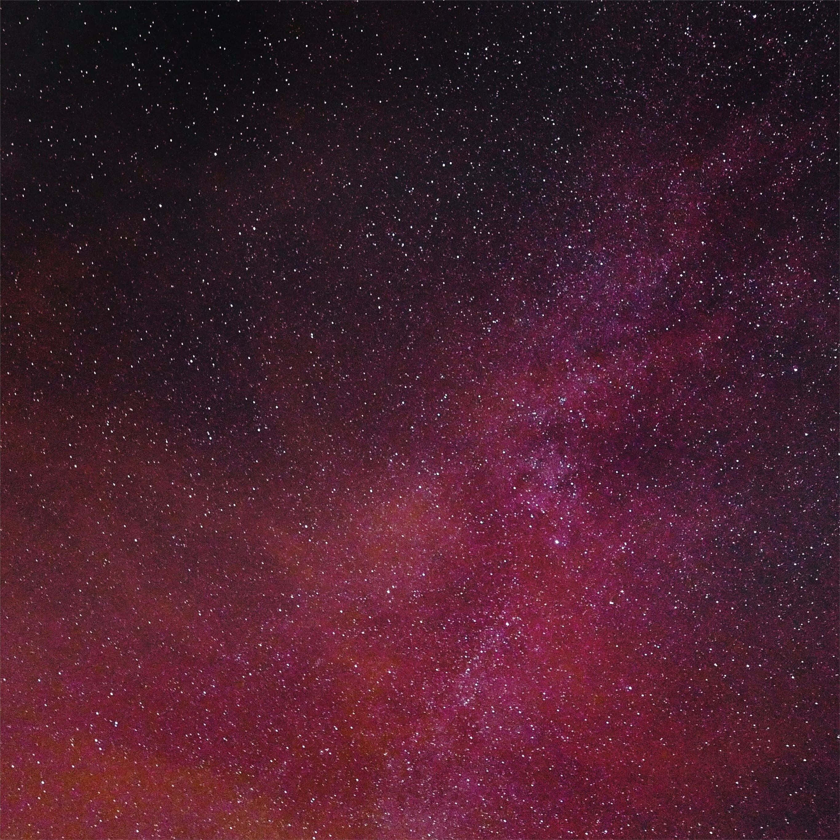 Pink Stars 桌布 壁紙 — 令人嘆為觀止的銀河景象，在繁星點綴的夜空中散發出深洋紅色和深紅色的光芒。
