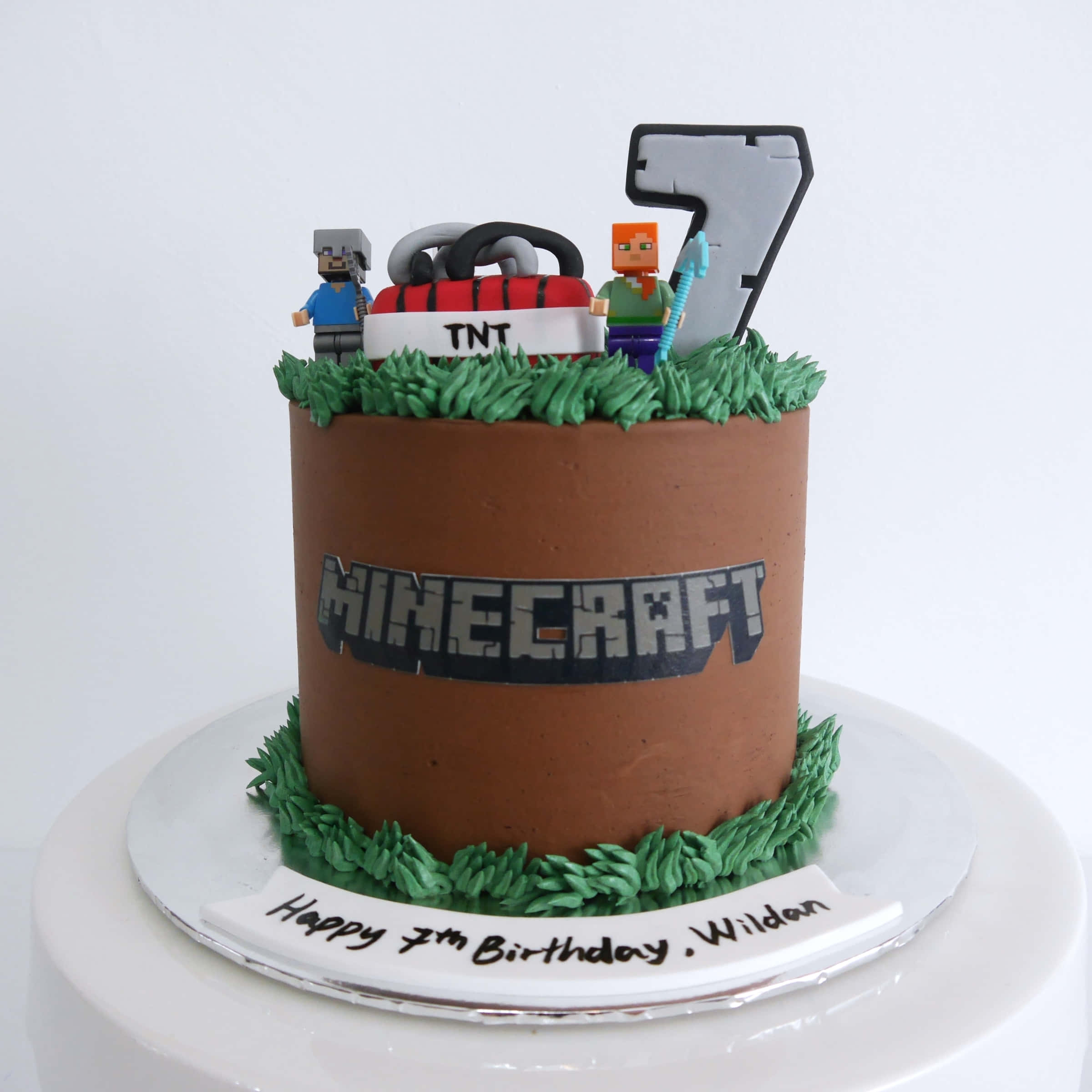 令人垂涎的Minecraft主題蛋糕 壁紙 — 一個以Minecraft為主題的生日蛋糕，上面有像素化角色和TNT裝飾，蛋糕體為棕色泥土紋理。