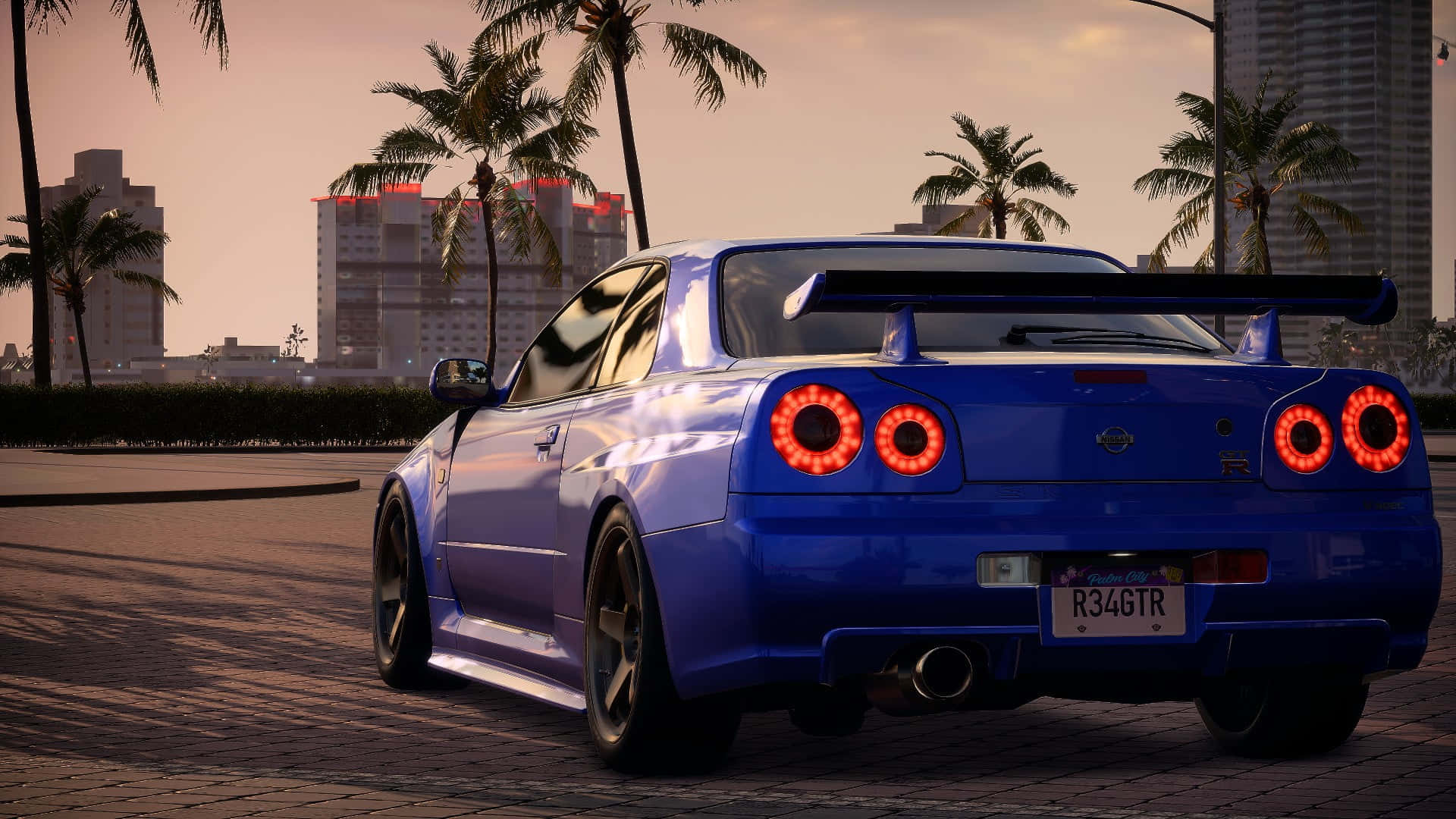 令人屏息的《Need For Speed Heat》遊戲背景 壁紙 — 一輛充滿活力的藍色日產Skyline R34 GT-R，帶有發光的紅色尾燈，停在日落時分棕櫚樹成蔭的城市街道上。