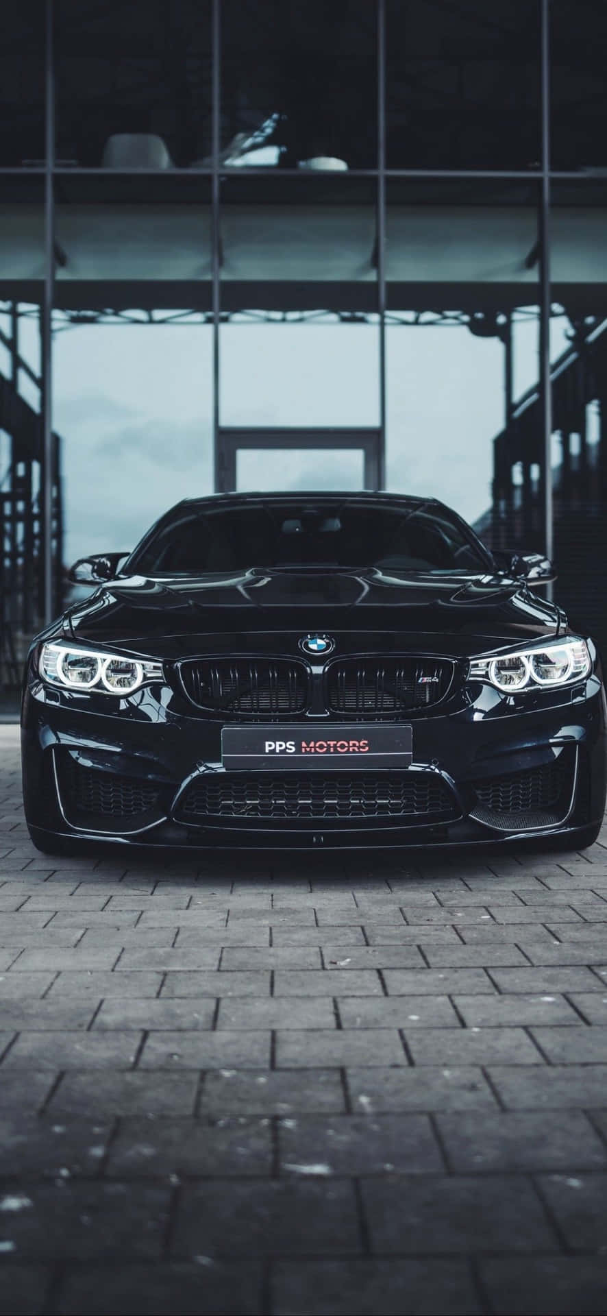 黑色BMW M4跑車停放在現代玻璃牆車庫的磚地上。