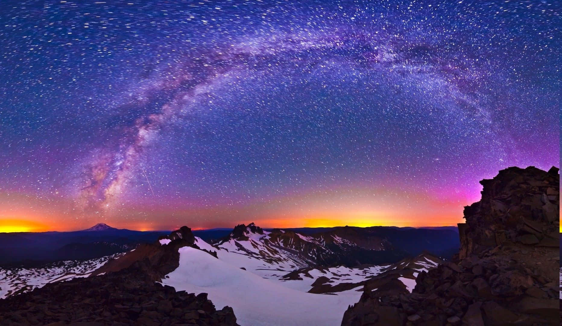Snowy Landscape 桌布 壁紙 — 令人屏息的夜空籠罩著積雪的山峰，銀河散發著鮮豔的紫色和橙色光芒。