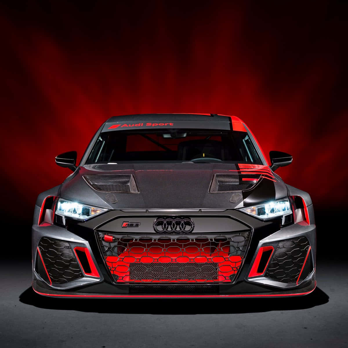 黑色 Audi 賽車，在工作室環境中帶有紅色燈光和格柵。 — 奧迪 GIF 壁紙
