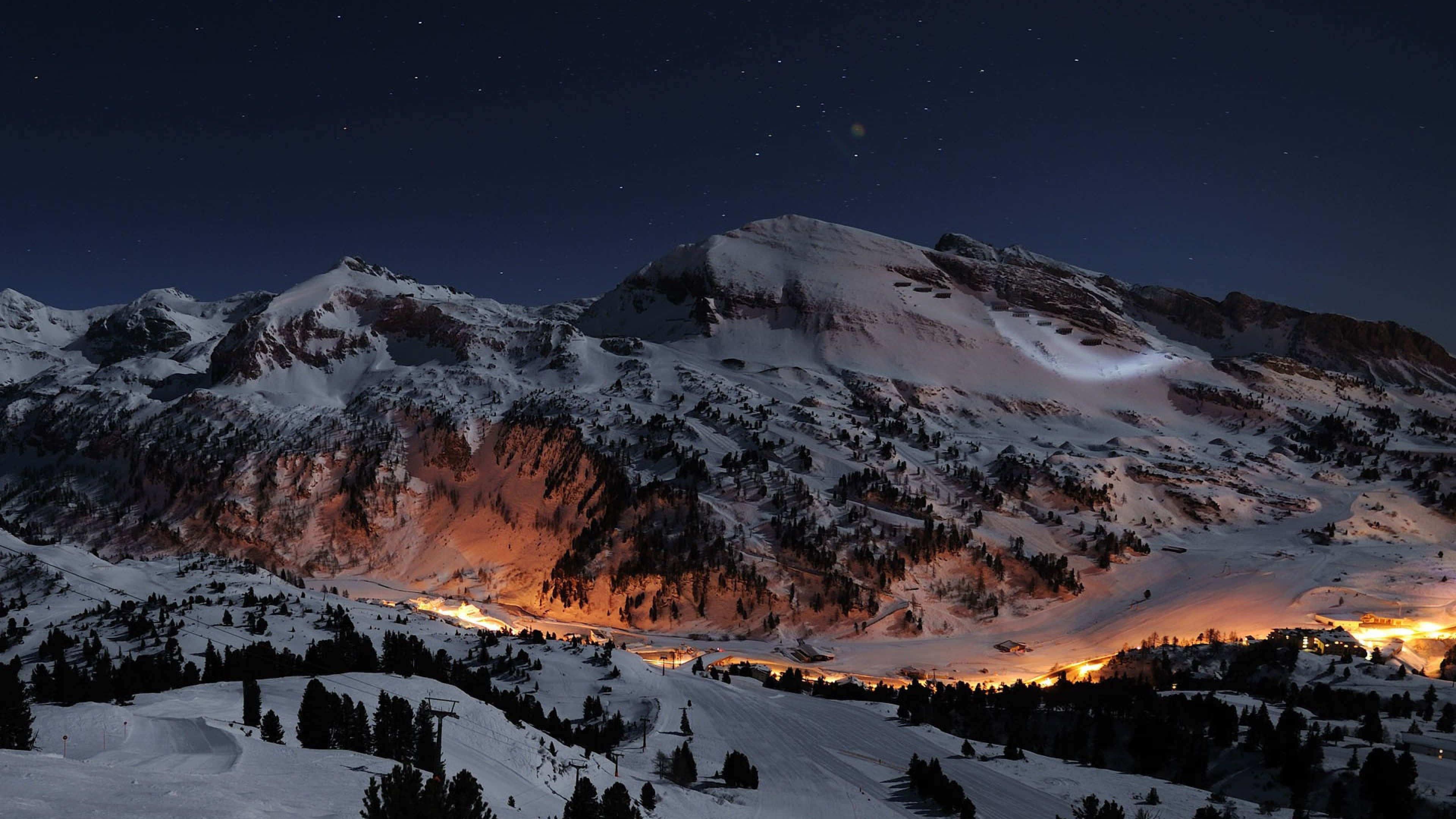 令人敬畏的山景 壁紙 — 白雪覆蓋的山峰，在星空下，山谷中溫暖的燈光閃爍。