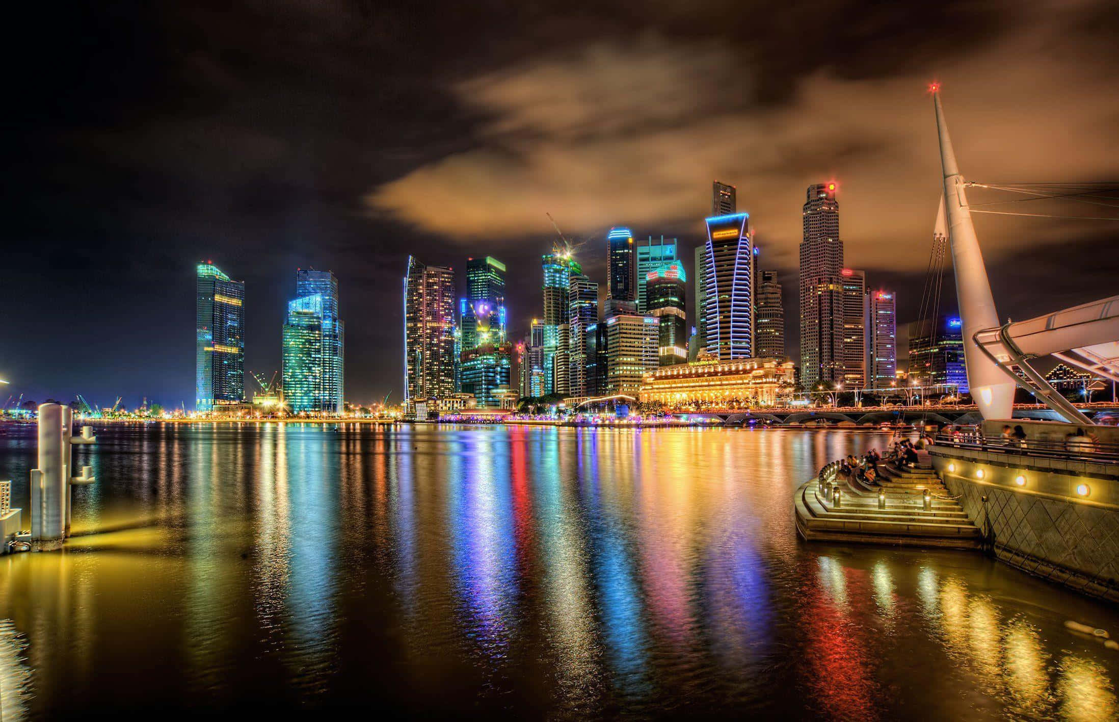 Singapore 桌布 壁紙 — 令人目眩的夜景，摩天大樓在霓虹色調中閃耀，倒映在平靜的水面上。