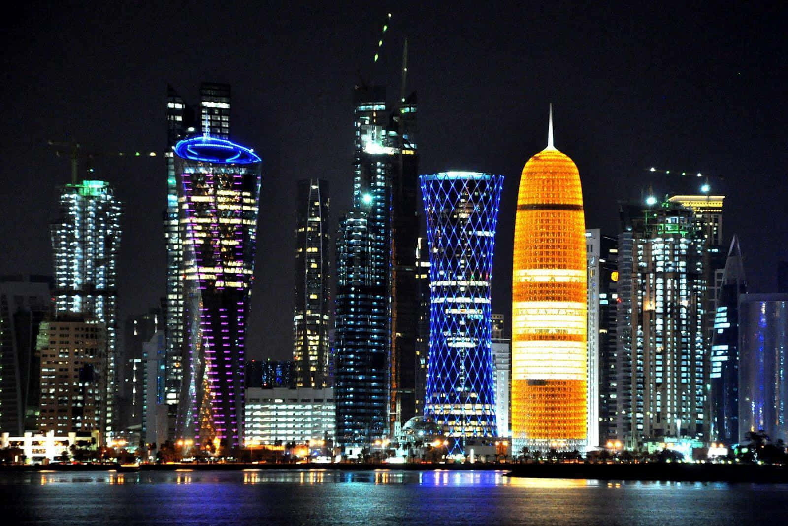 Qatar 桌布 壁紙 — 令人目眩的現代摩天大樓夜景，閃爍著鮮豔的霓虹燈光，倒映在平靜的水面上。