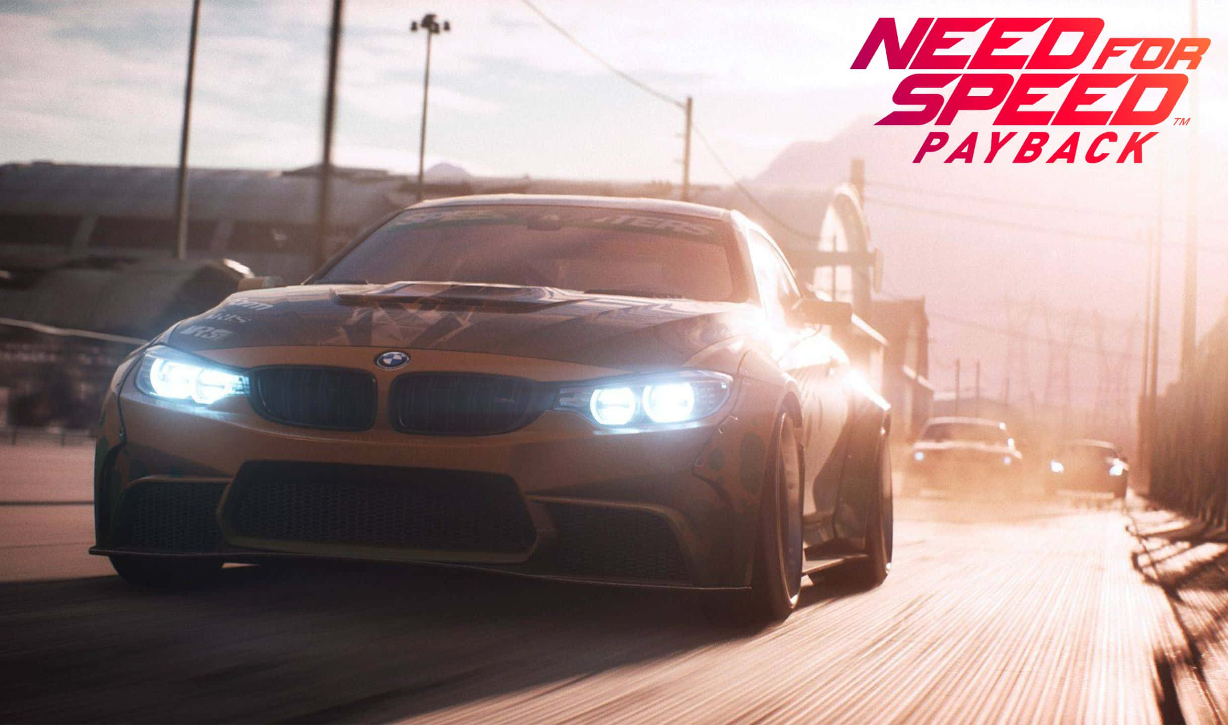 令人著迷的 2440x1440《Need For Speed Payback》遊戲背景 壁紙 — 一輛金色寶馬賽車在日落時分沿著塵土飛揚的城市街道疾馳，車頭燈閃爍，並帶有遊戲標題疊加。