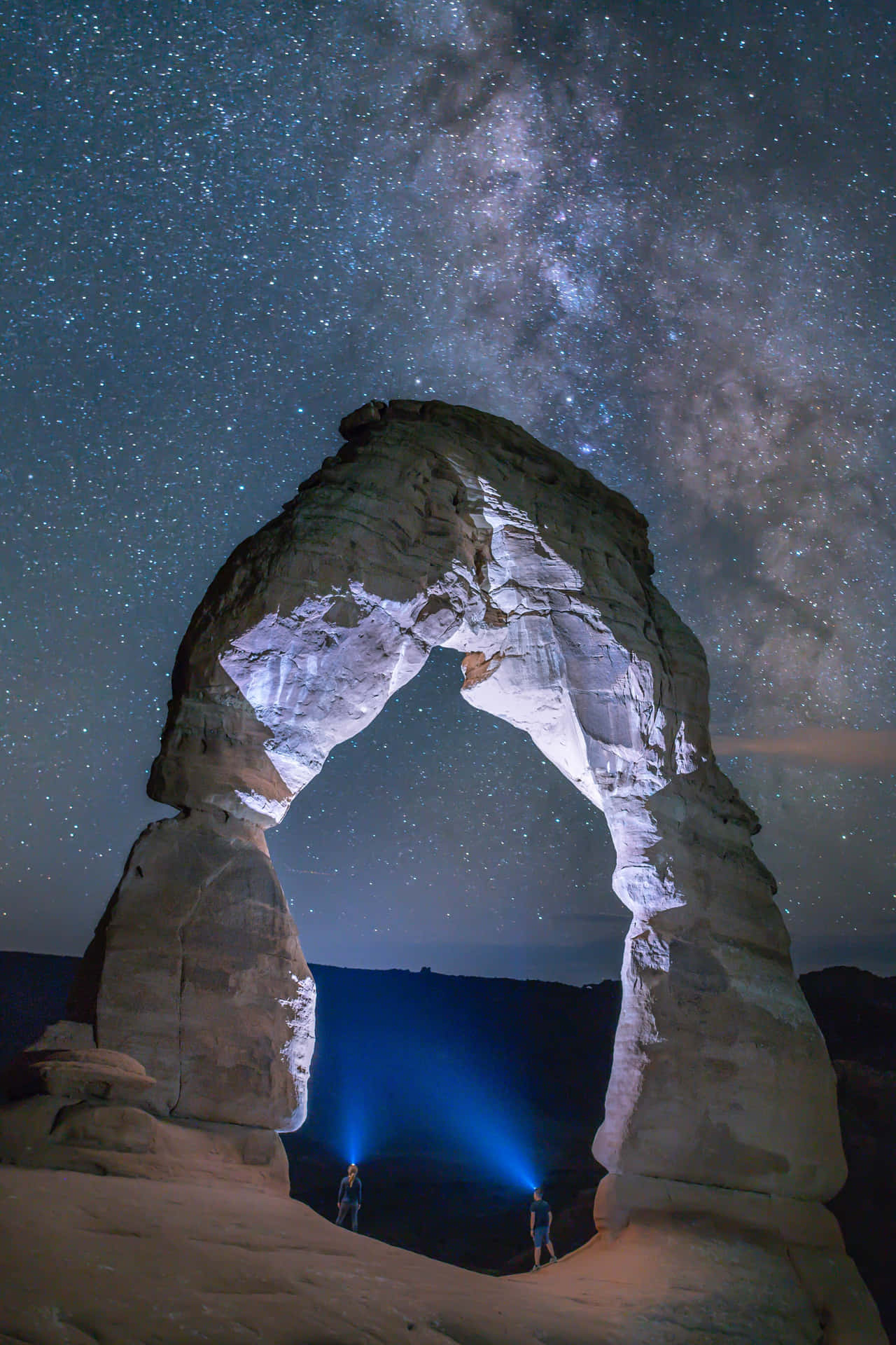 兩人在星空下站在發光的石拱門下，銀河可見。