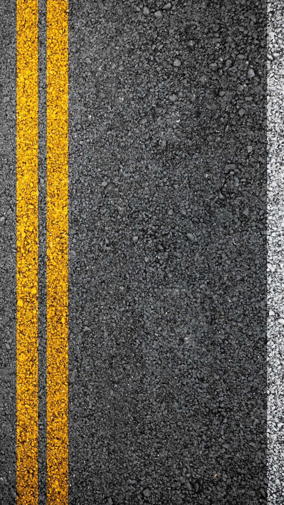 令人著迷的紋理圖案 壁紙 — 紋理瀝青道路的特寫，帶有粗黃色雙線和白色邊緣標記。
