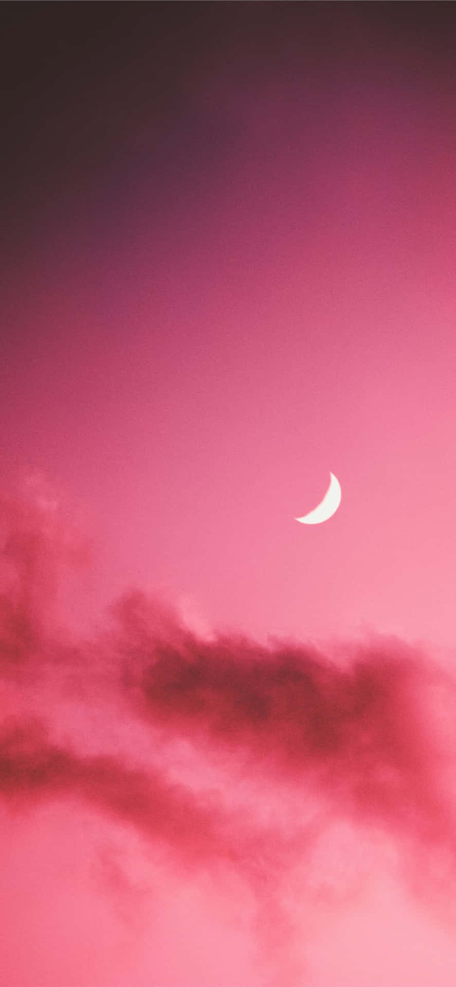 粉紅色暮色天空中的月牙與柔和的雲彩。