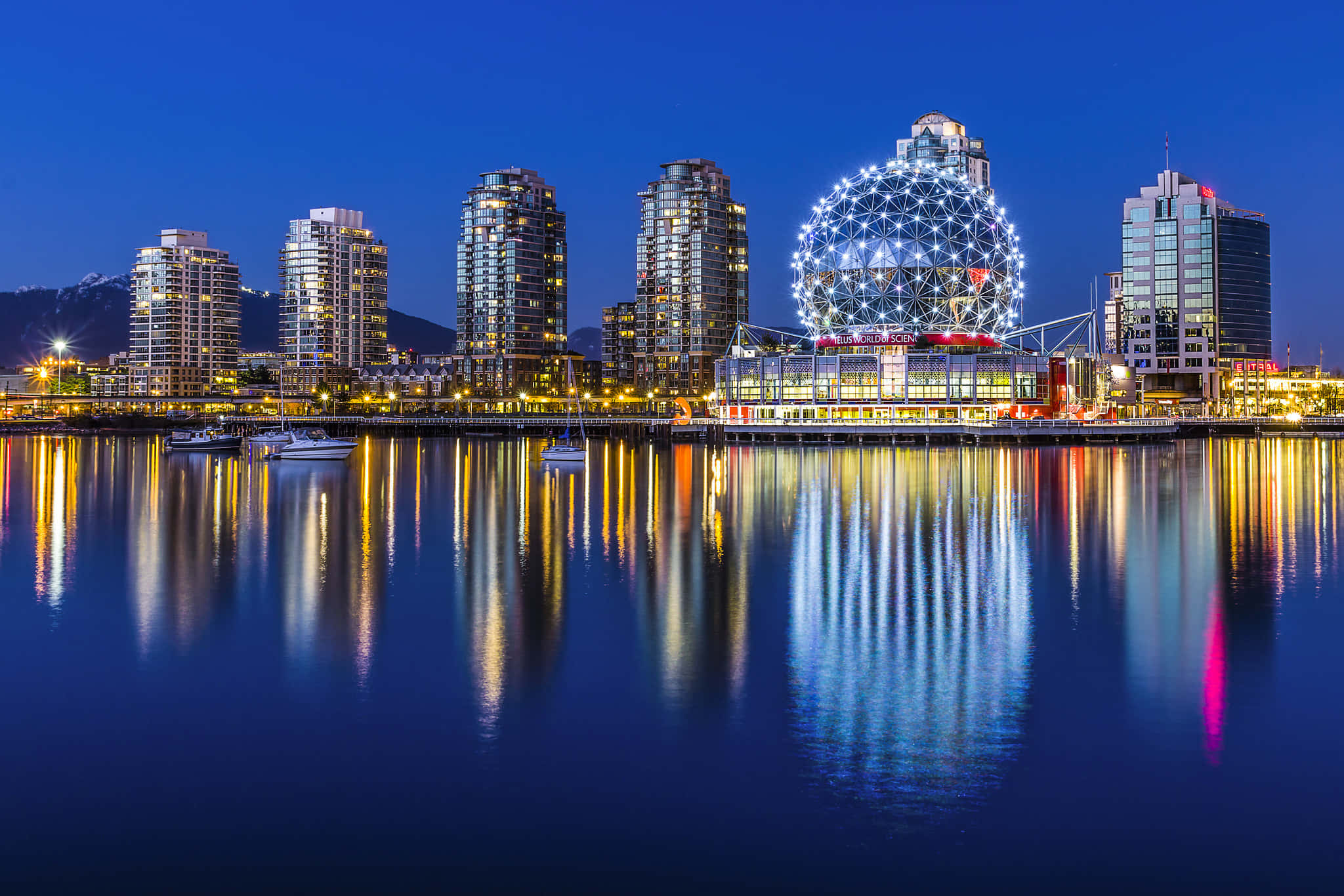 Canada 桌布 壁紙 — 令人驚嘆的夜景城市景觀，燈火通明的摩天大樓和發光的球形建築物倒映在平靜的水面上。