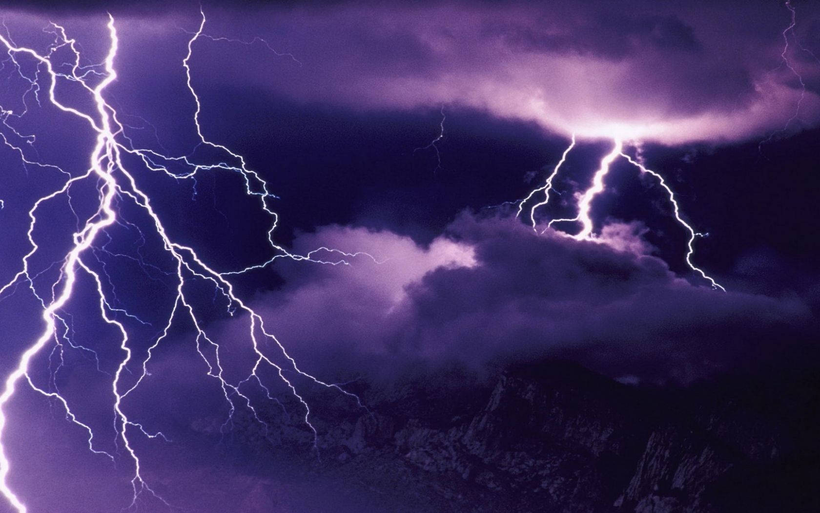 紫色閃電照亮山峰上方的暴風雲。