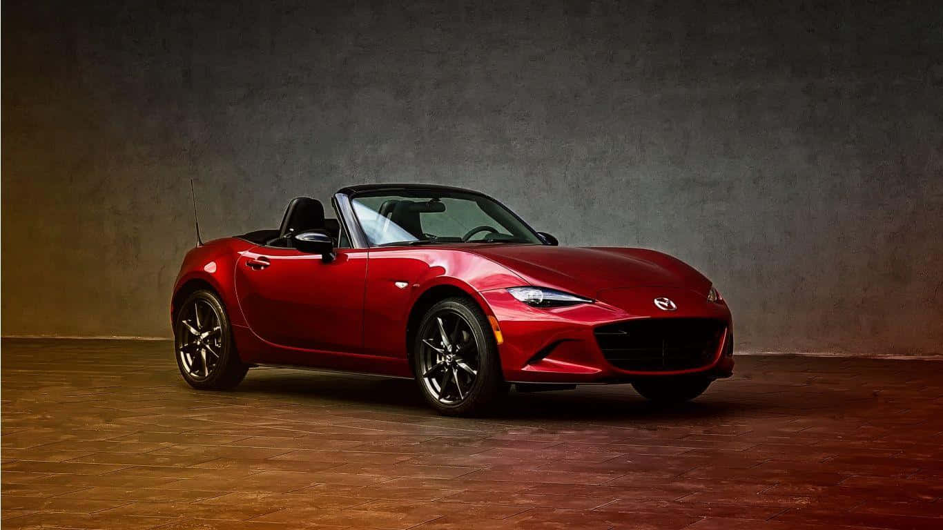 攝影棚內有紋理牆壁和溫暖燈光的紅色Mazda Miata開篷車。
