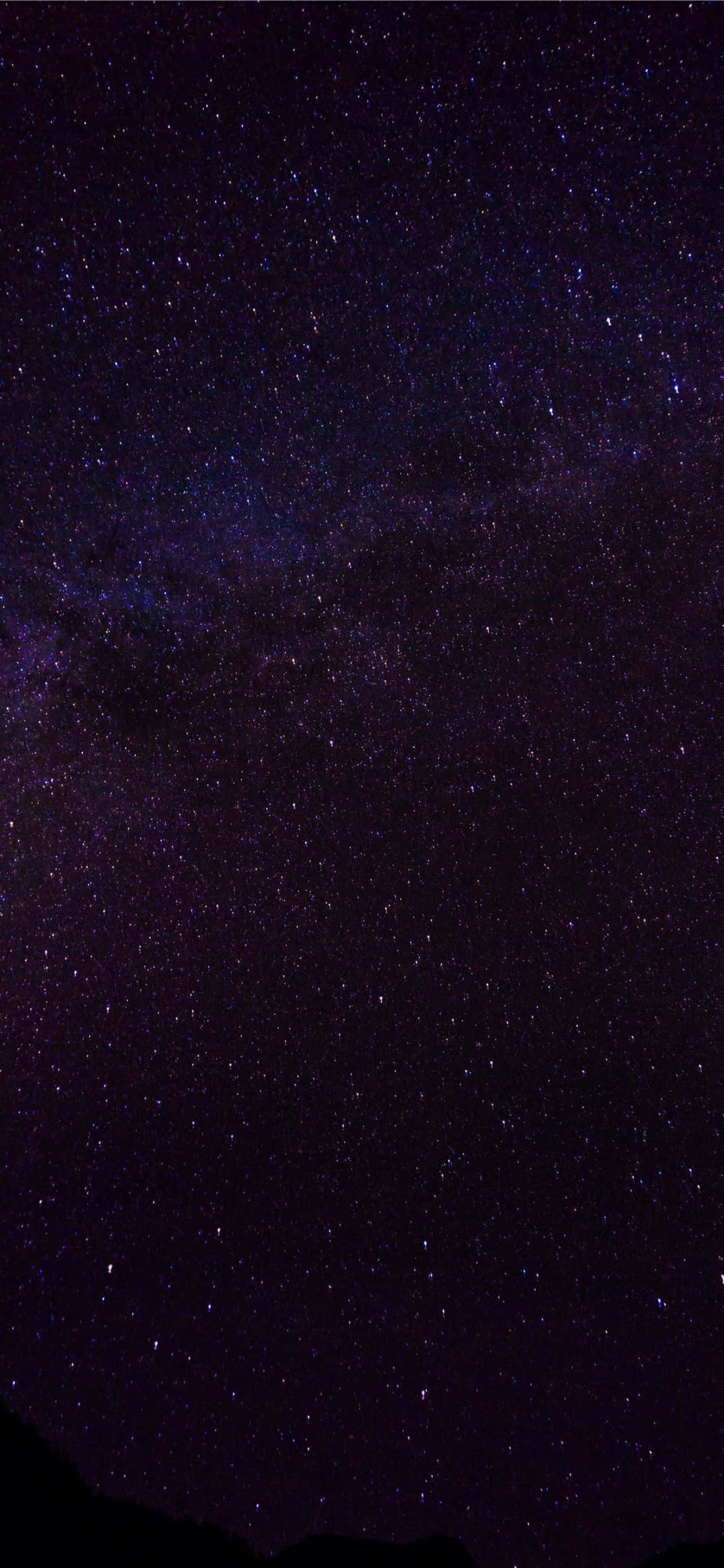 iPhone 13 Pro 桌布 壁紙 — 令人驚嘆的銀河系景觀，在深紫色夜空下，無數星星閃耀在黑暗的山脈輪廓之上。