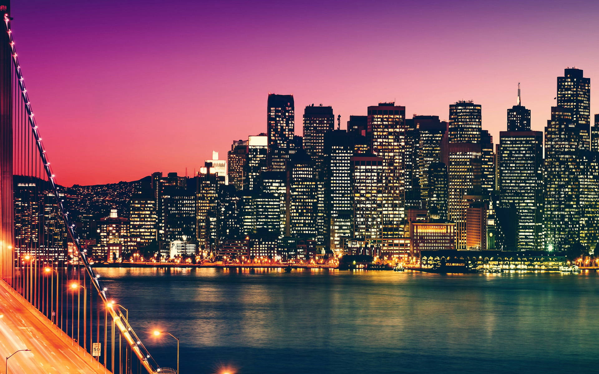 San Francisco Phone 桌布 壁紙 — 令人驚嘆的黃昏城市天際線景觀，發光的摩天大樓倒映在平靜的水面上，旁邊是一座亮燈的吊橋。
